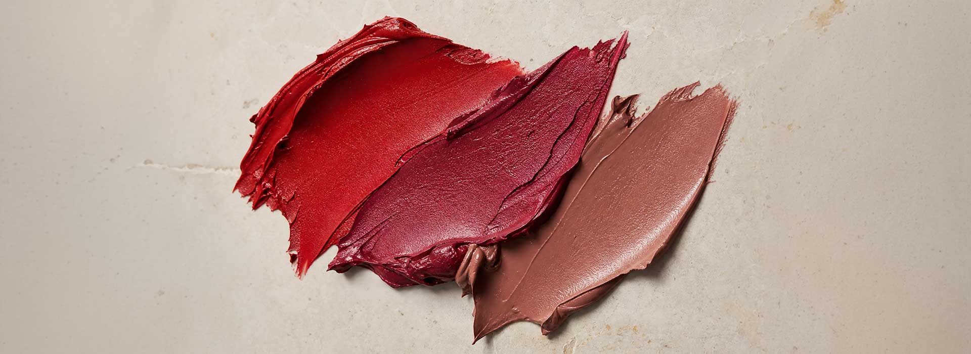 A textured, editorial blend of lipstick shades highlighting their creamy consistency.